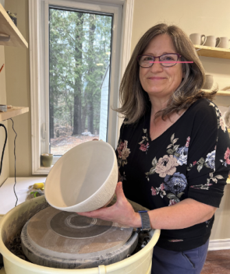 Lady holding a pottery bowl made by her in grey color