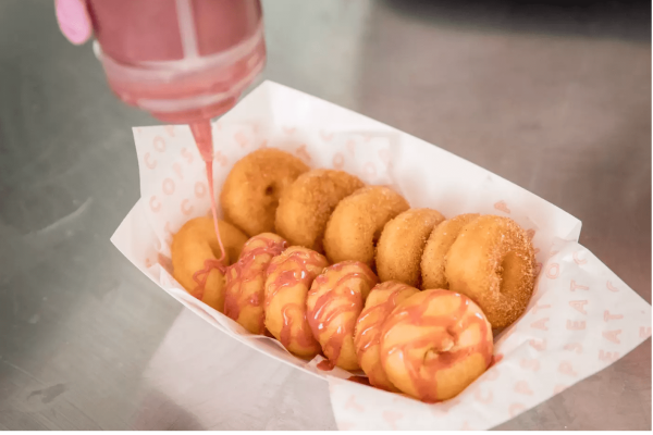 Small donuts with person pouring strawberry maple syrup on them