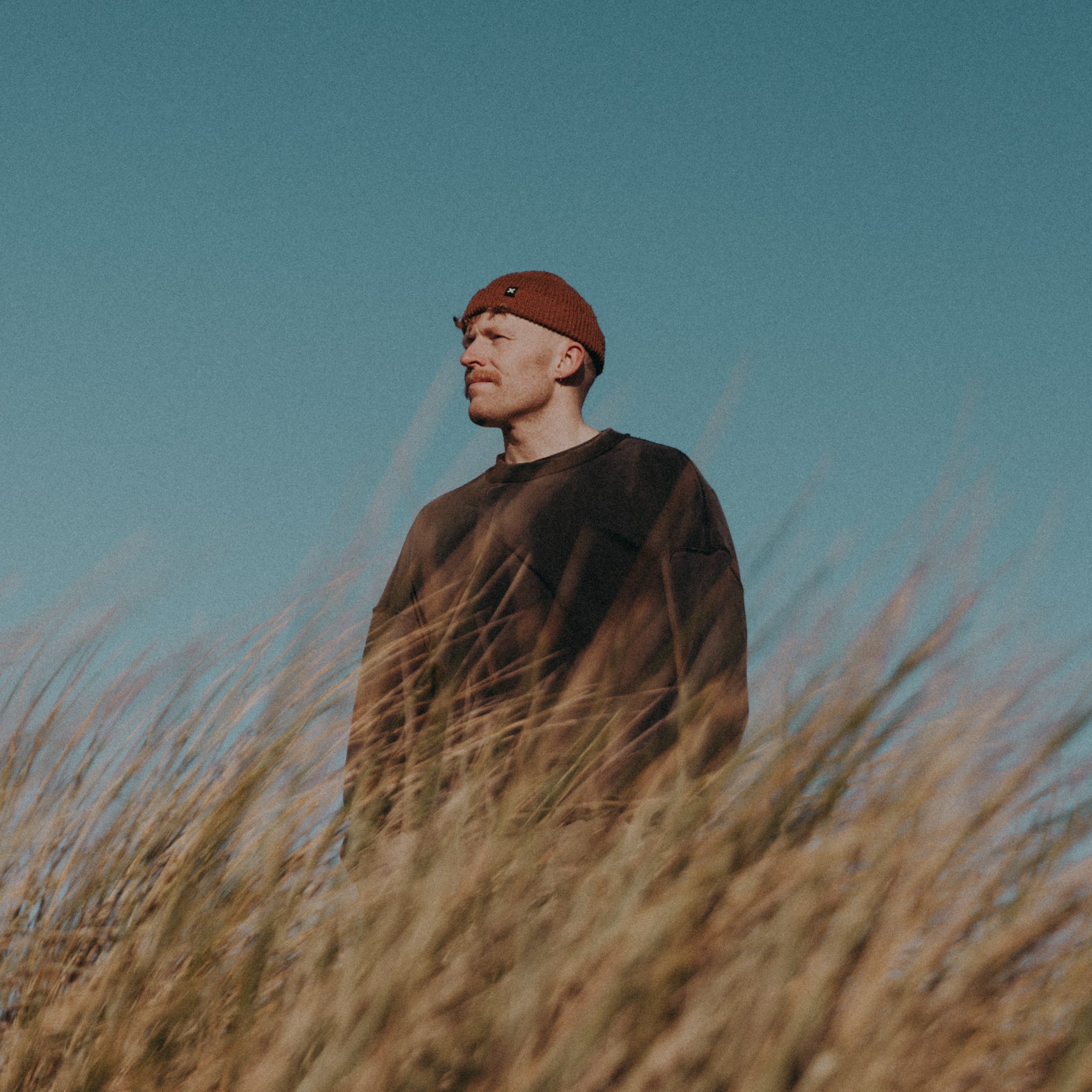 A Man standing on a field looking at a distance towards left 